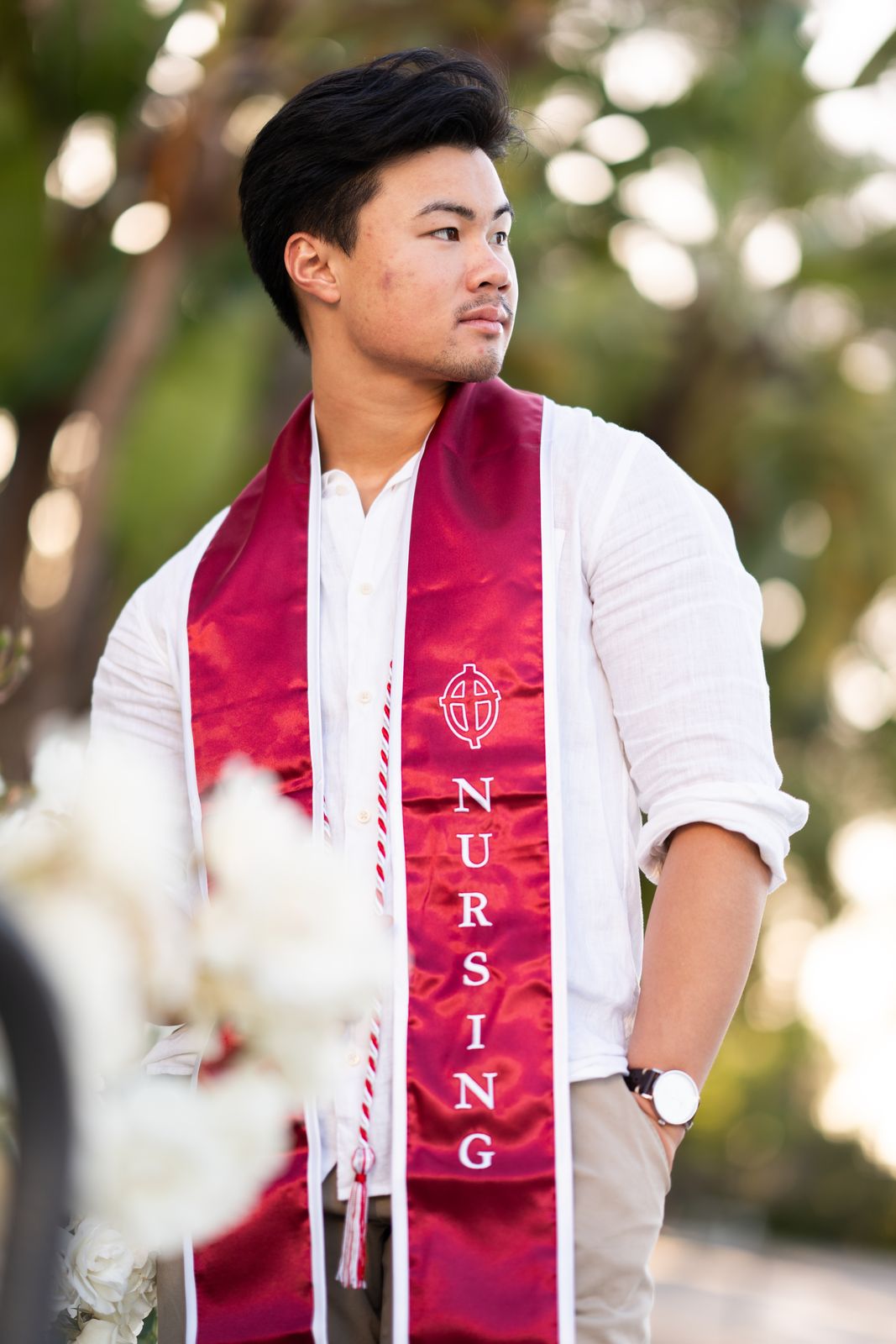 Nursing graduate in a red stole among white blossoms