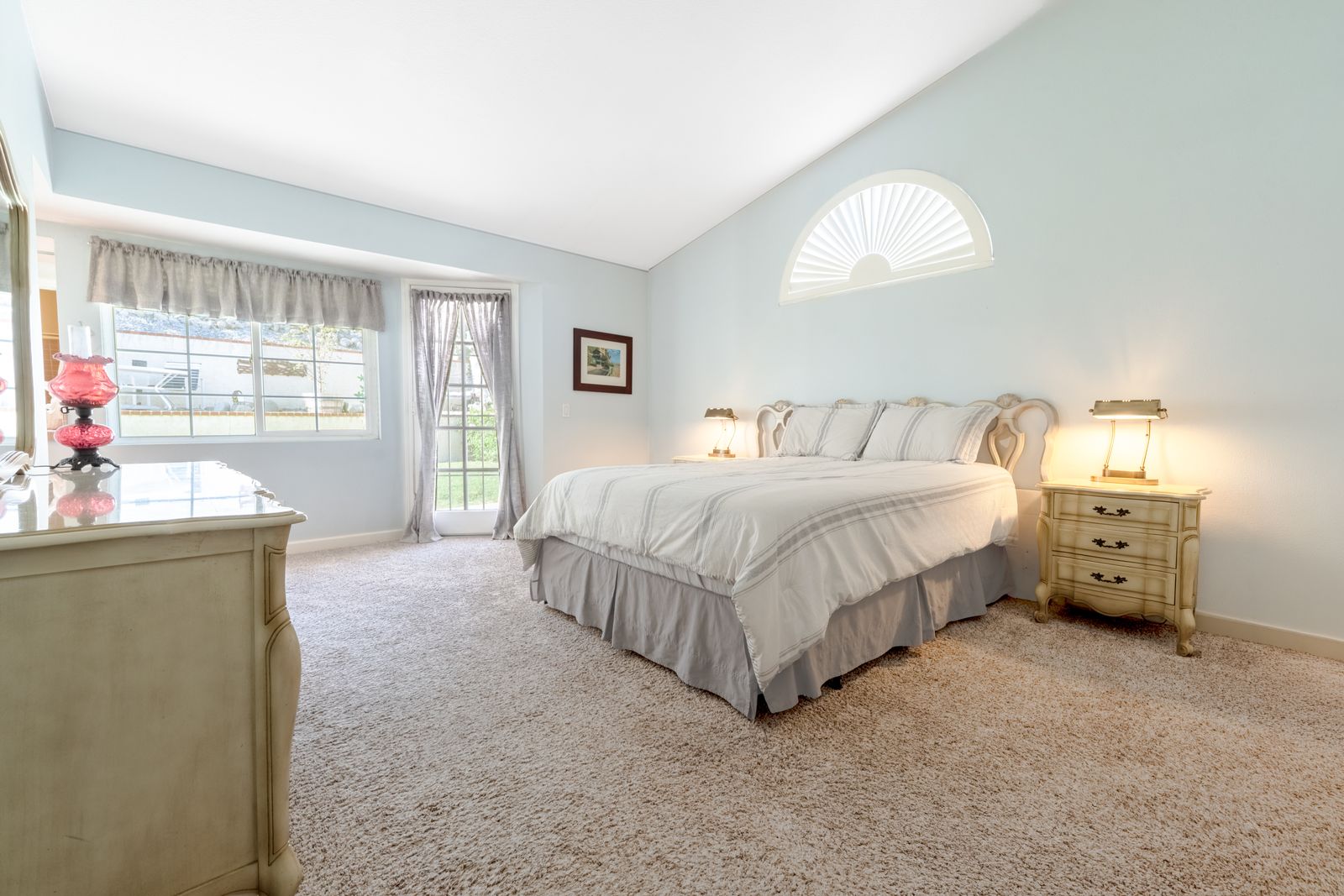 Bright bedroom with a vaulted ceiling and arched window